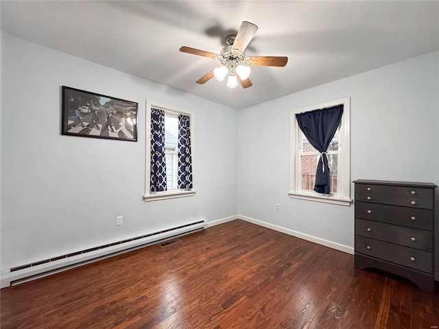 spare room featuring ceiling fan, dark hardwood / wood-style floors, and a baseboard heating unit