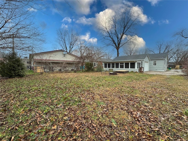 rear view of house featuring a lawn and a sunroom