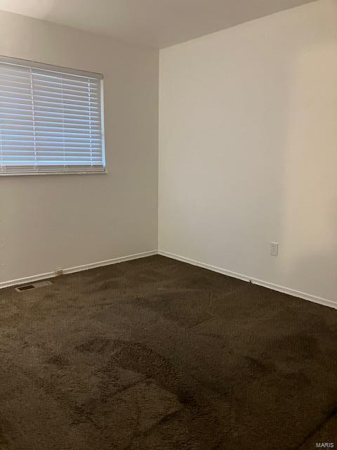 unfurnished room with dark carpet