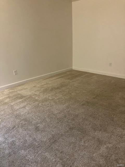 spare room featuring dark carpet and baseboards