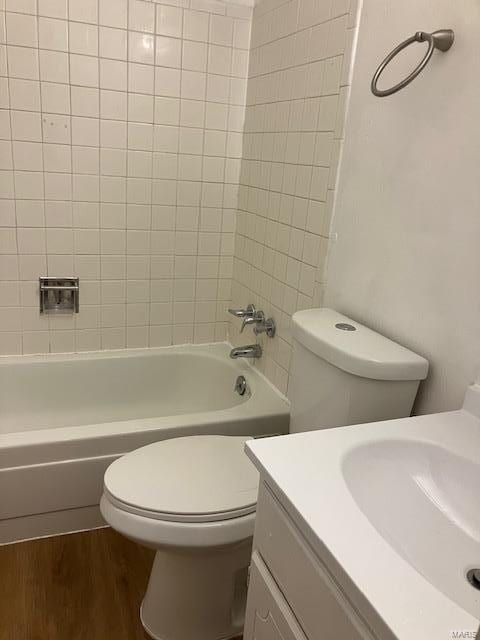 bathroom with toilet, wood finished floors, vanity, and  shower combination
