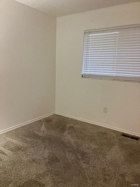 empty room featuring visible vents, baseboards, and dark carpet