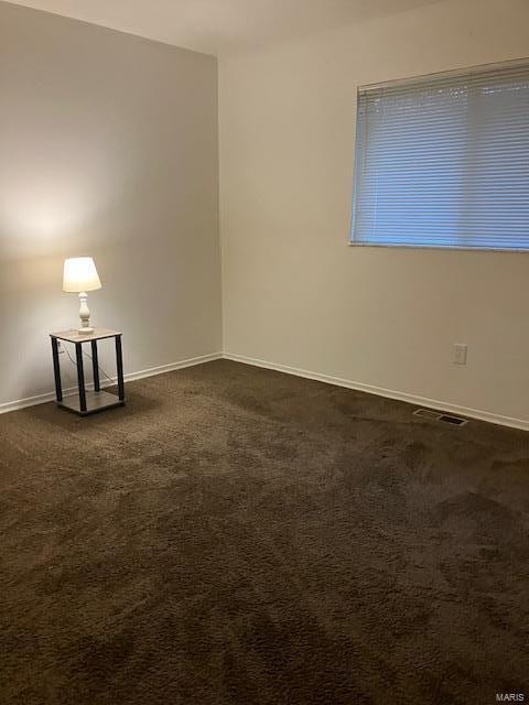 unfurnished room featuring dark carpet, baseboards, and visible vents
