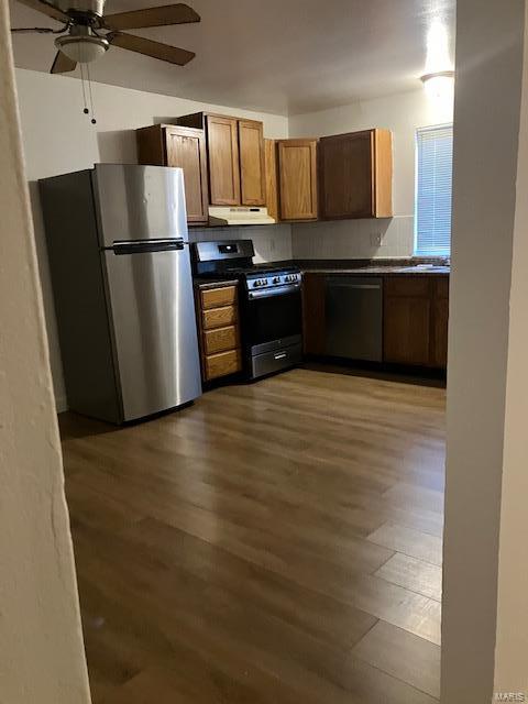kitchen featuring gas stove, a ceiling fan, exhaust hood, freestanding refrigerator, and dark countertops