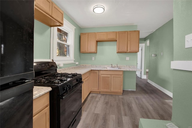 kitchen featuring sink, black appliances, light brown cabinets, and light hardwood / wood-style floors