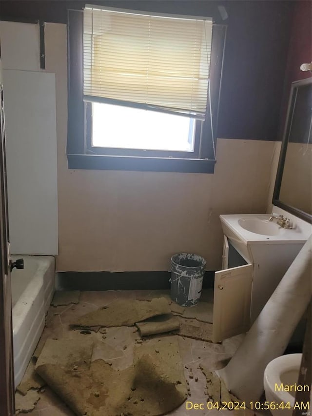 bathroom featuring a washtub, vanity, and toilet