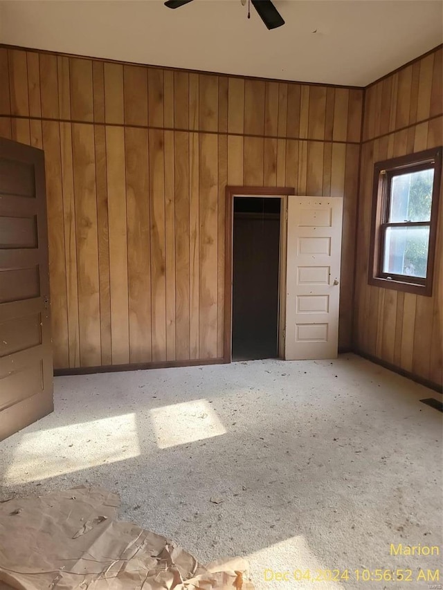 unfurnished bedroom featuring wooden walls, a closet, and ceiling fan