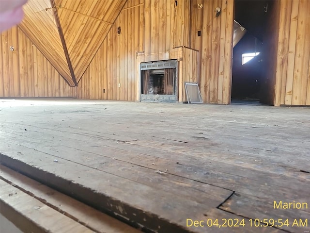 unfurnished living room featuring wooden walls, a fireplace, and high vaulted ceiling