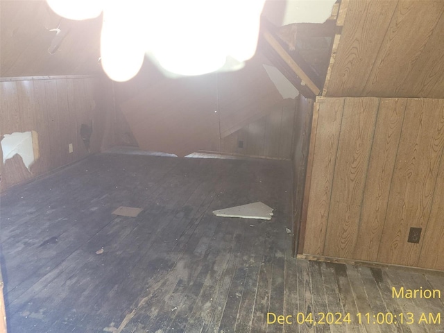 bonus room with wooden walls, dark hardwood / wood-style flooring, and lofted ceiling