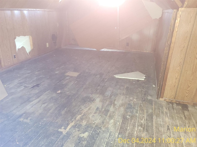 spare room featuring wood walls, dark hardwood / wood-style flooring, and lofted ceiling