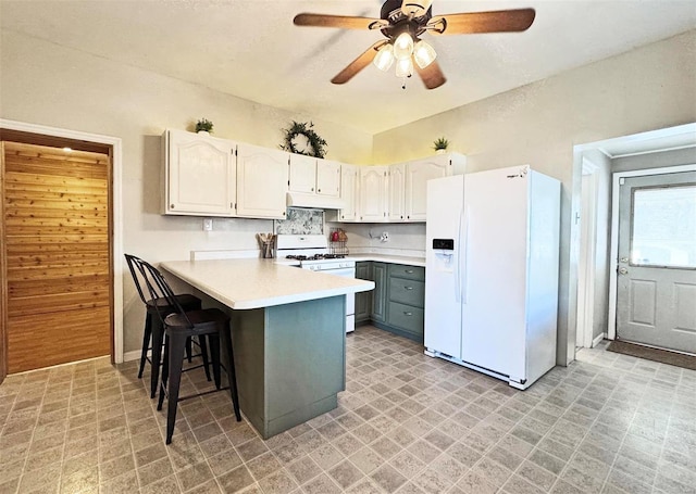 kitchen featuring white cabinetry, a kitchen bar, ceiling fan, kitchen peninsula, and white appliances