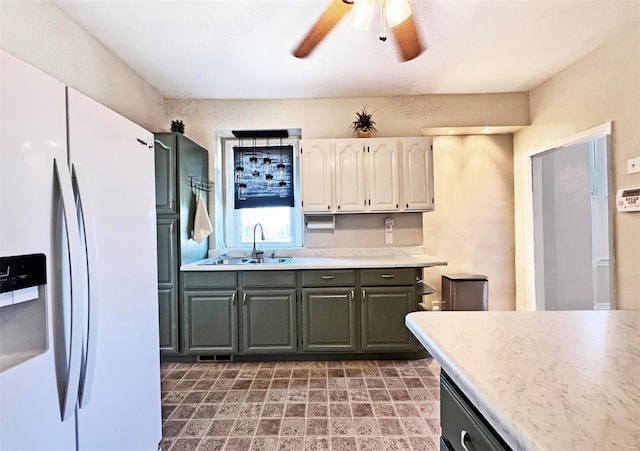 kitchen featuring white cabinetry, ceiling fan, white refrigerator with ice dispenser, and sink