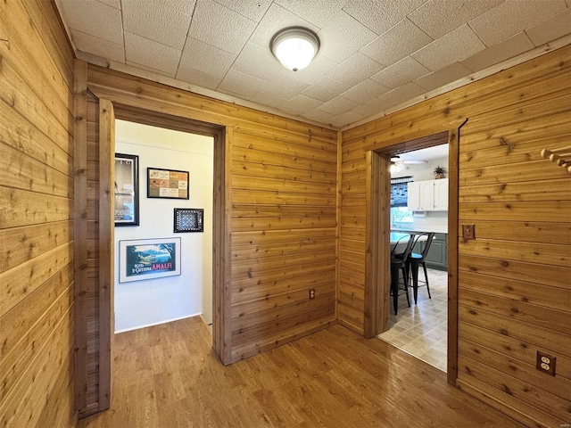 corridor with wooden walls and light wood-type flooring