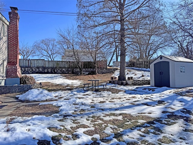 snowy yard featuring a storage shed