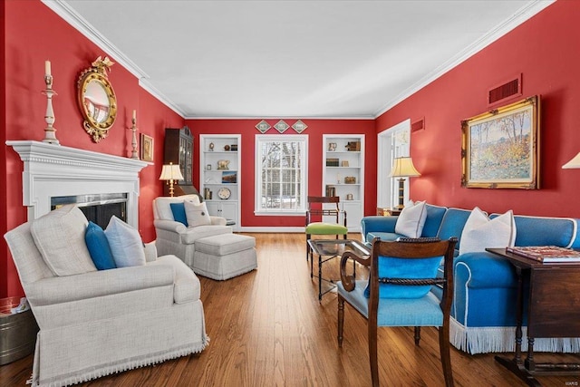 living room featuring hardwood / wood-style floors, built in shelves, and ornamental molding