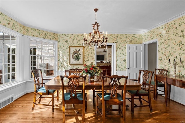 dining area featuring an inviting chandelier, hardwood / wood-style flooring, and crown molding