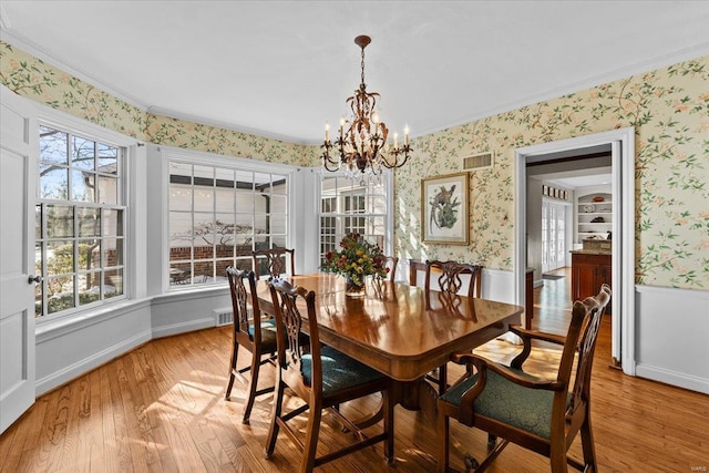 dining area featuring crown molding, a notable chandelier, and light hardwood / wood-style flooring