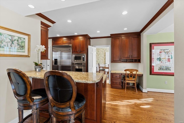 kitchen with ornamental molding, built in appliances, light stone counters, kitchen peninsula, and light hardwood / wood-style flooring