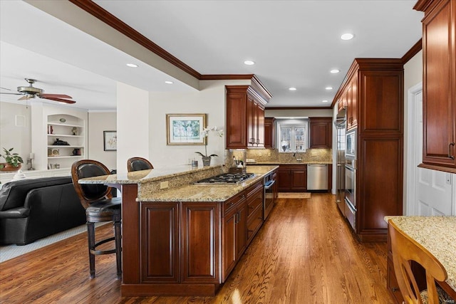 kitchen featuring dark wood-type flooring, a breakfast bar, kitchen peninsula, and appliances with stainless steel finishes