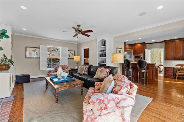 living room featuring hardwood / wood-style flooring, ornamental molding, and ceiling fan