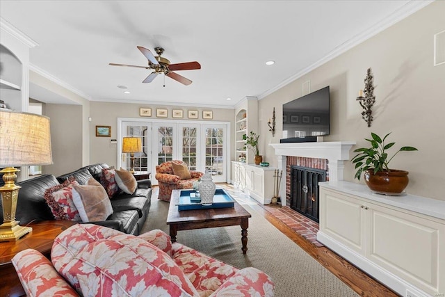 living room with ornamental molding, a brick fireplace, hardwood / wood-style floors, and ceiling fan