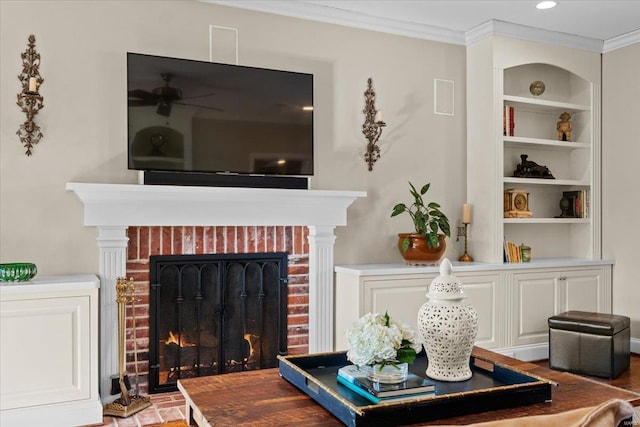 living room featuring crown molding, a brick fireplace, ceiling fan, and built in shelves