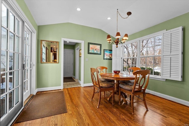 dining space featuring lofted ceiling, wood-type flooring, and a chandelier