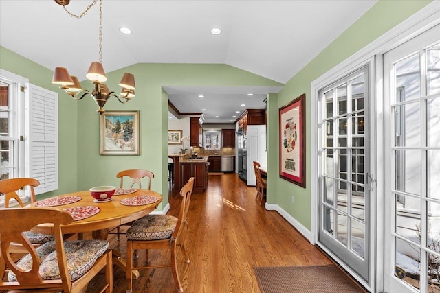 dining space featuring lofted ceiling, dark hardwood / wood-style floors, and a notable chandelier