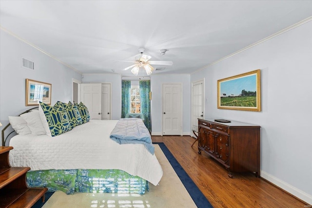 bedroom with crown molding, ceiling fan, dark hardwood / wood-style flooring, and two closets