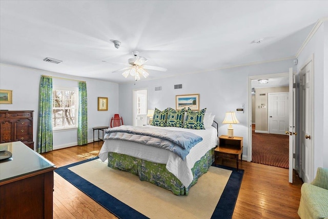 bedroom with crown molding, ceiling fan, and light hardwood / wood-style flooring