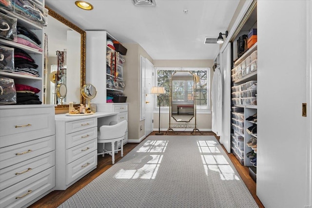 spacious closet featuring dark wood-type flooring and built in desk