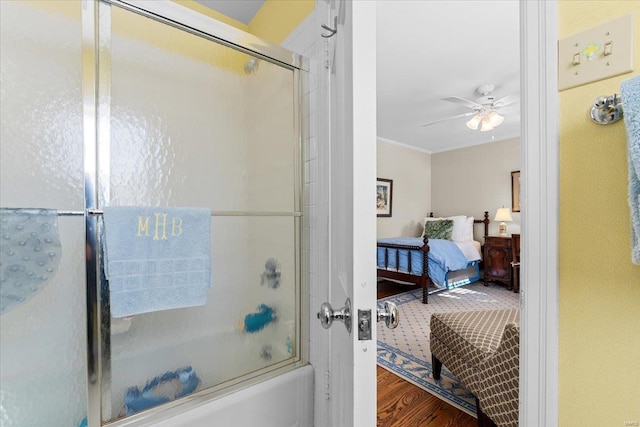 bathroom featuring ceiling fan, ornamental molding, wood-type flooring, and bath / shower combo with glass door