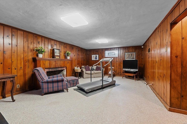 workout area with light colored carpet, a fireplace, a textured ceiling, and wood walls