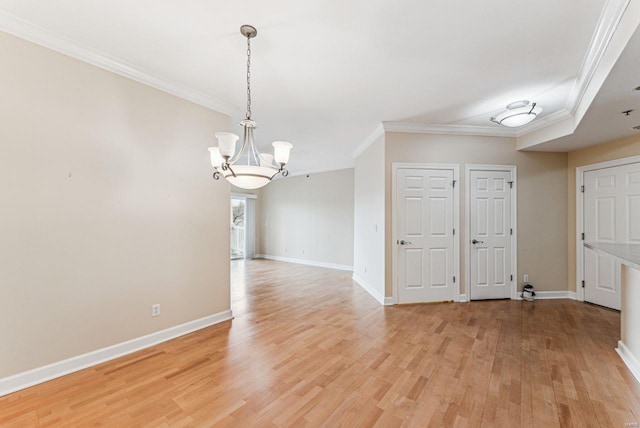 unfurnished room with light wood-type flooring, a notable chandelier, and ornamental molding