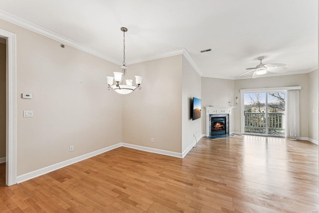 unfurnished living room with ceiling fan with notable chandelier, crown molding, and light hardwood / wood-style floors