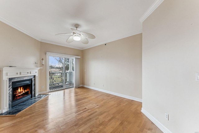 unfurnished living room with ceiling fan, a premium fireplace, crown molding, and light hardwood / wood-style floors