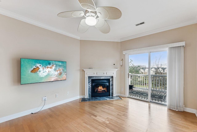 unfurnished living room with ceiling fan, a fireplace, ornamental molding, and light hardwood / wood-style floors