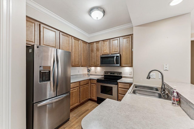 kitchen with appliances with stainless steel finishes, decorative backsplash, sink, light hardwood / wood-style floors, and crown molding