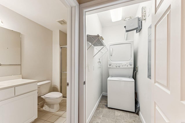 bathroom featuring walk in shower, vanity, toilet, tile patterned flooring, and stacked washer and dryer