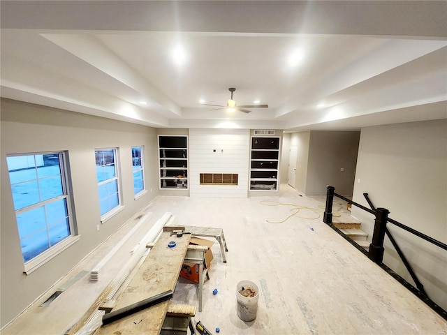 interior space with built in shelves, ceiling fan, and a tray ceiling