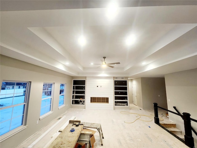 unfurnished living room with ceiling fan and a tray ceiling