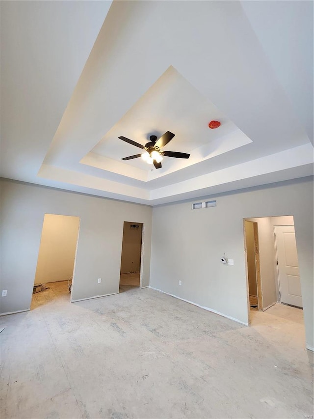 unfurnished room with ceiling fan and a tray ceiling