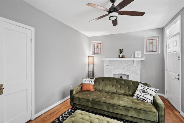 sitting room featuring hardwood / wood-style flooring, ceiling fan, and a brick fireplace