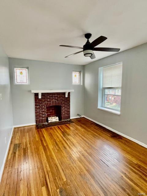 unfurnished living room with a fireplace, wood-type flooring, plenty of natural light, and ceiling fan