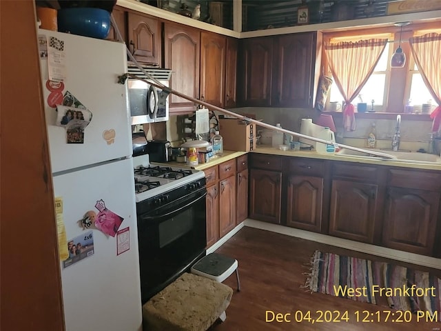 kitchen with dark hardwood / wood-style flooring, white appliances, and sink