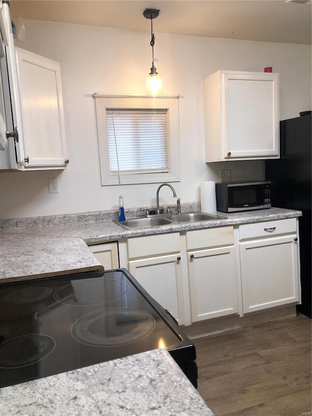 kitchen featuring white cabinetry, sink, dark hardwood / wood-style flooring, pendant lighting, and black range