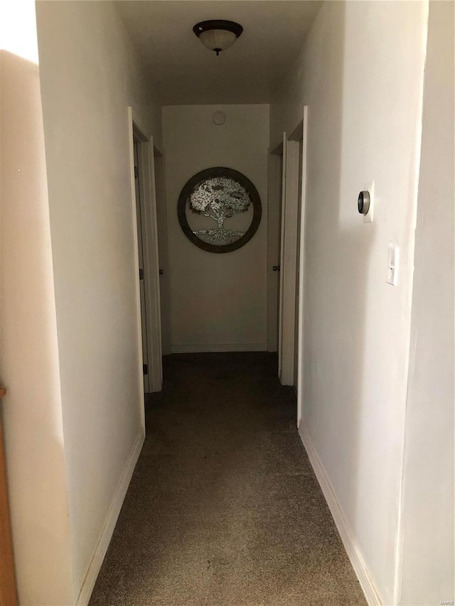 hallway featuring dark colored carpet