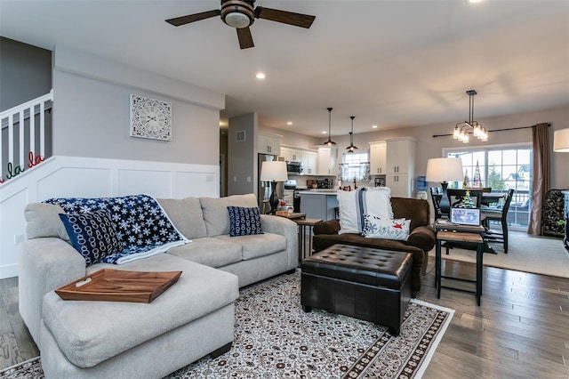 living room with hardwood / wood-style flooring and ceiling fan with notable chandelier