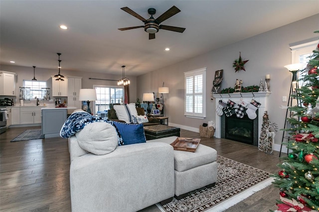 living room with dark hardwood / wood-style flooring, sink, ceiling fan with notable chandelier, and plenty of natural light