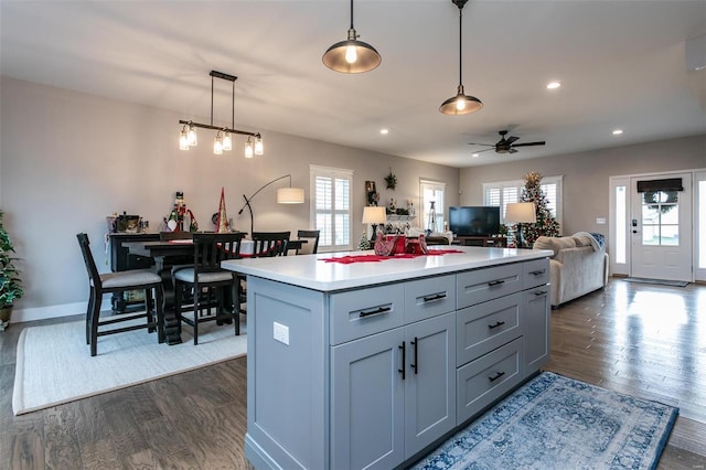 kitchen featuring gray cabinets, a kitchen island, dark hardwood / wood-style floors, decorative light fixtures, and ceiling fan